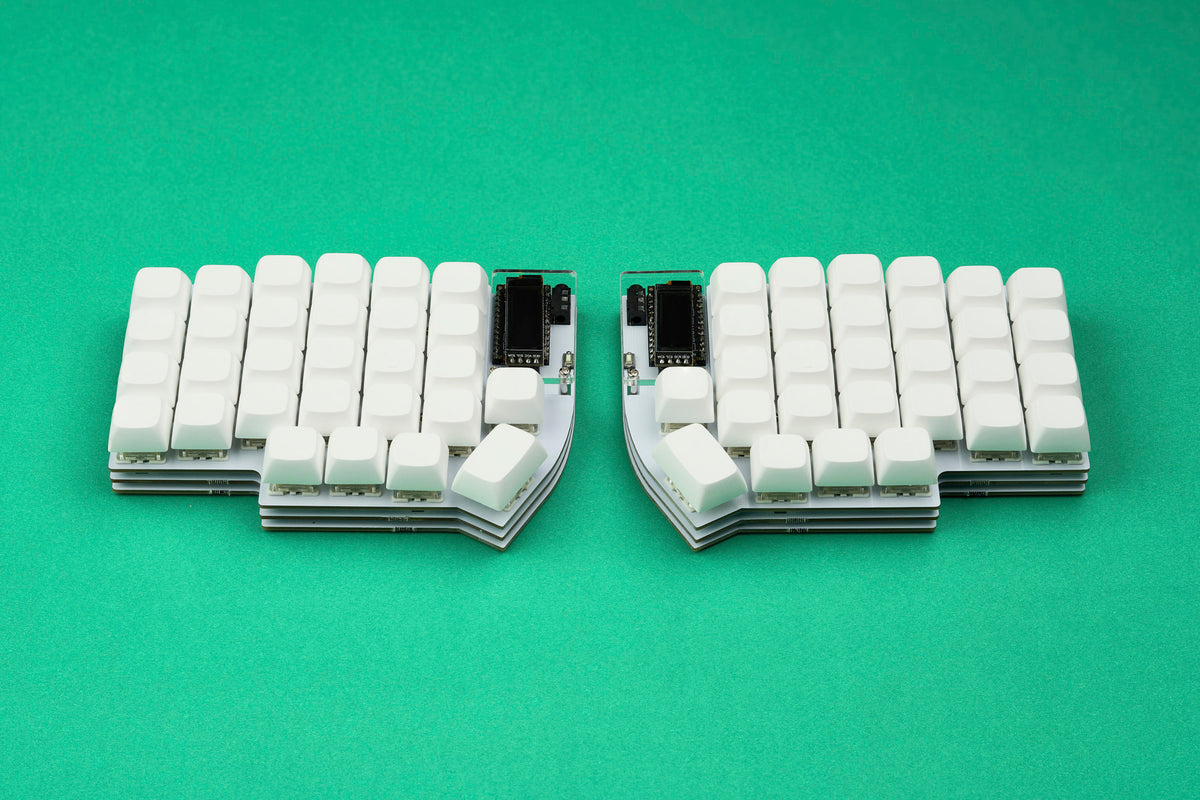 A white Lily58 keyboard with white keycaps shown from straight angle on top of a bright green backdrop.