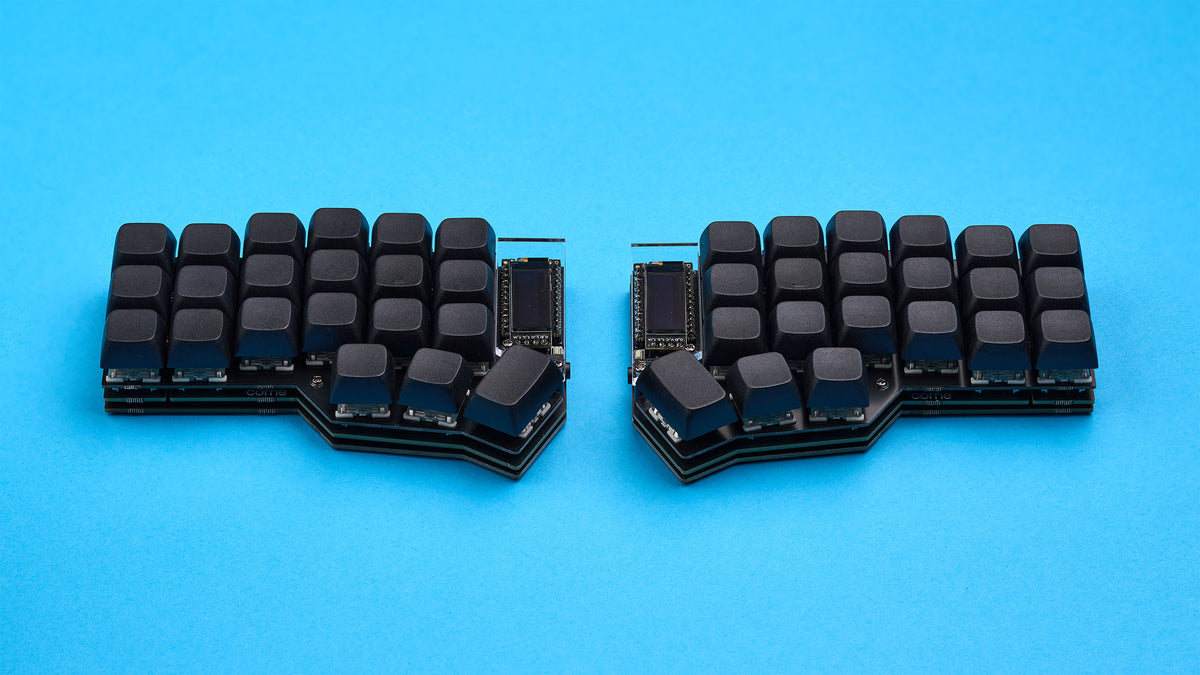 Top-down view of Corne DIY keyboard with black keycaps and OLED screens on a vibrant blue background.