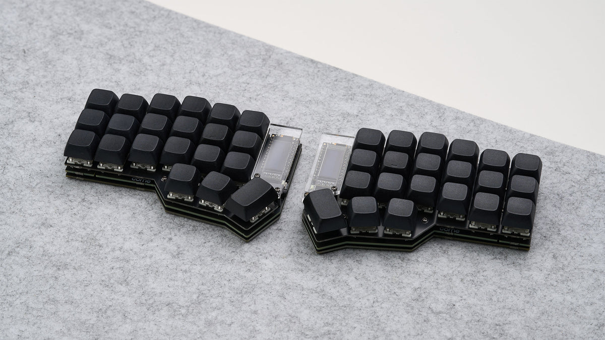 Corne DIY keyboard with all-black keycaps and OLED screens, assembled on gray felt deskmat.