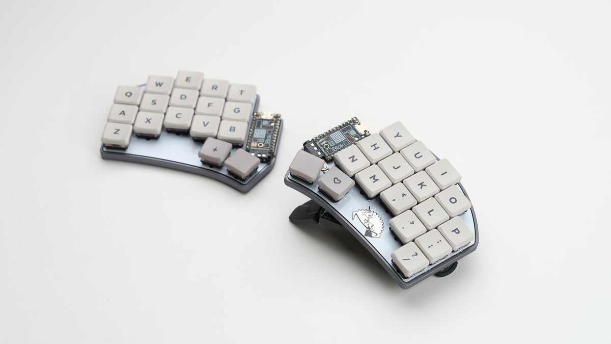 Angled view of Crab Broom keyboard halves with light keycaps on a white background