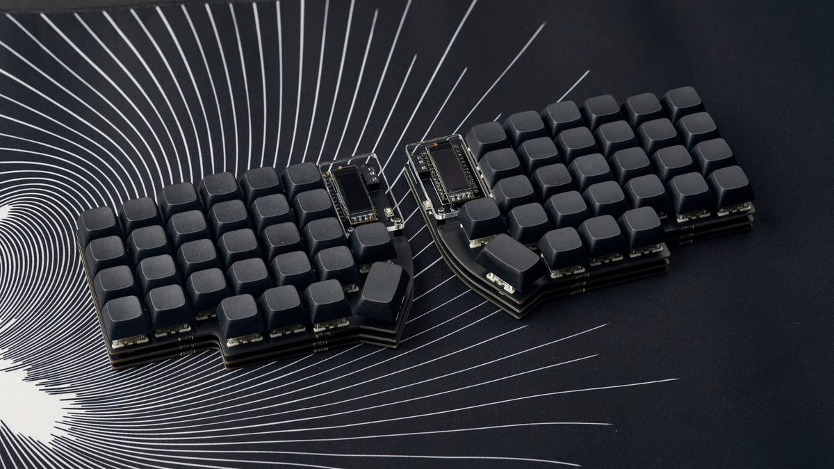 A black Lily58 keyboard with dark keycaps resting on a black-and-white spiral patterned desk mat.
