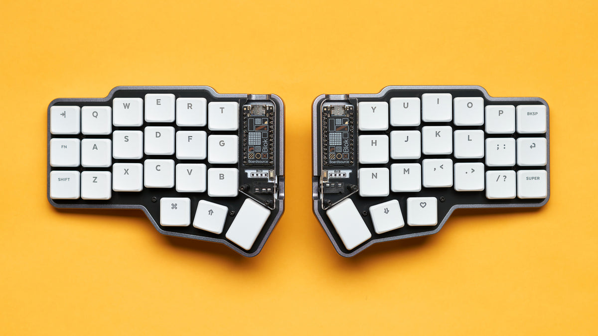 Flat lay of Unicorne LP tented keyboard with white keycaps and black/yellow case on yellow background