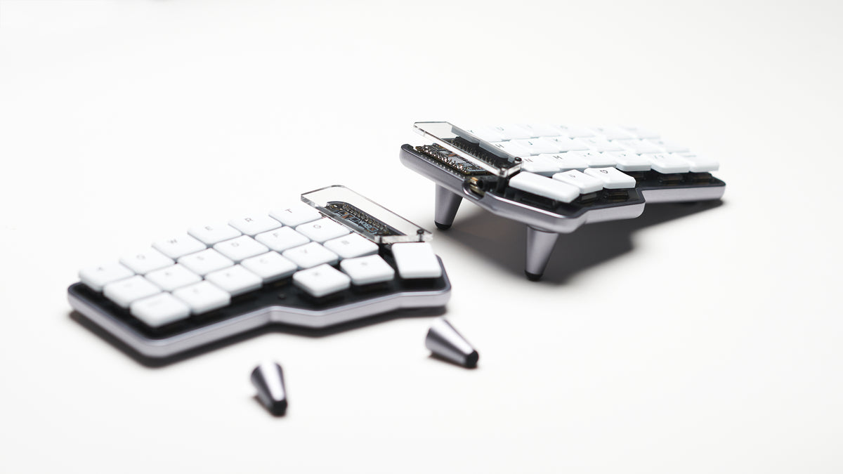 Unicorne LP keyboard angled with included parts like screws and tenting legs shown next to it on white background