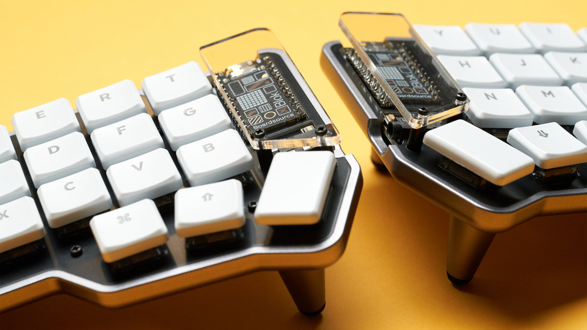 Side view of the Unicorne LP keyboard showing low-profile case height and installed white Choc keycaps on yellow background