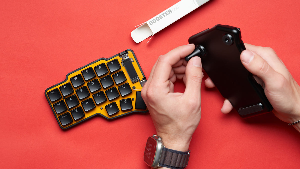 Hands installing tenting kit into black and yellow Unicorne LP keyboard case during assembly