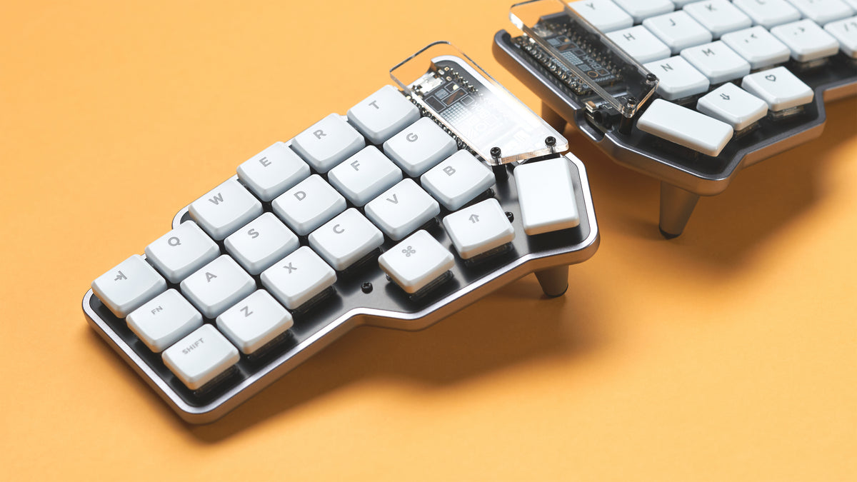 Close-up of both halves of the Unicorne LP keyboard with white keycaps and tenting legs on yellow background